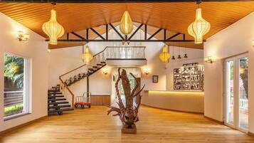 A spacious lobby with a wooden floor, a staircase, and a reception desk.
