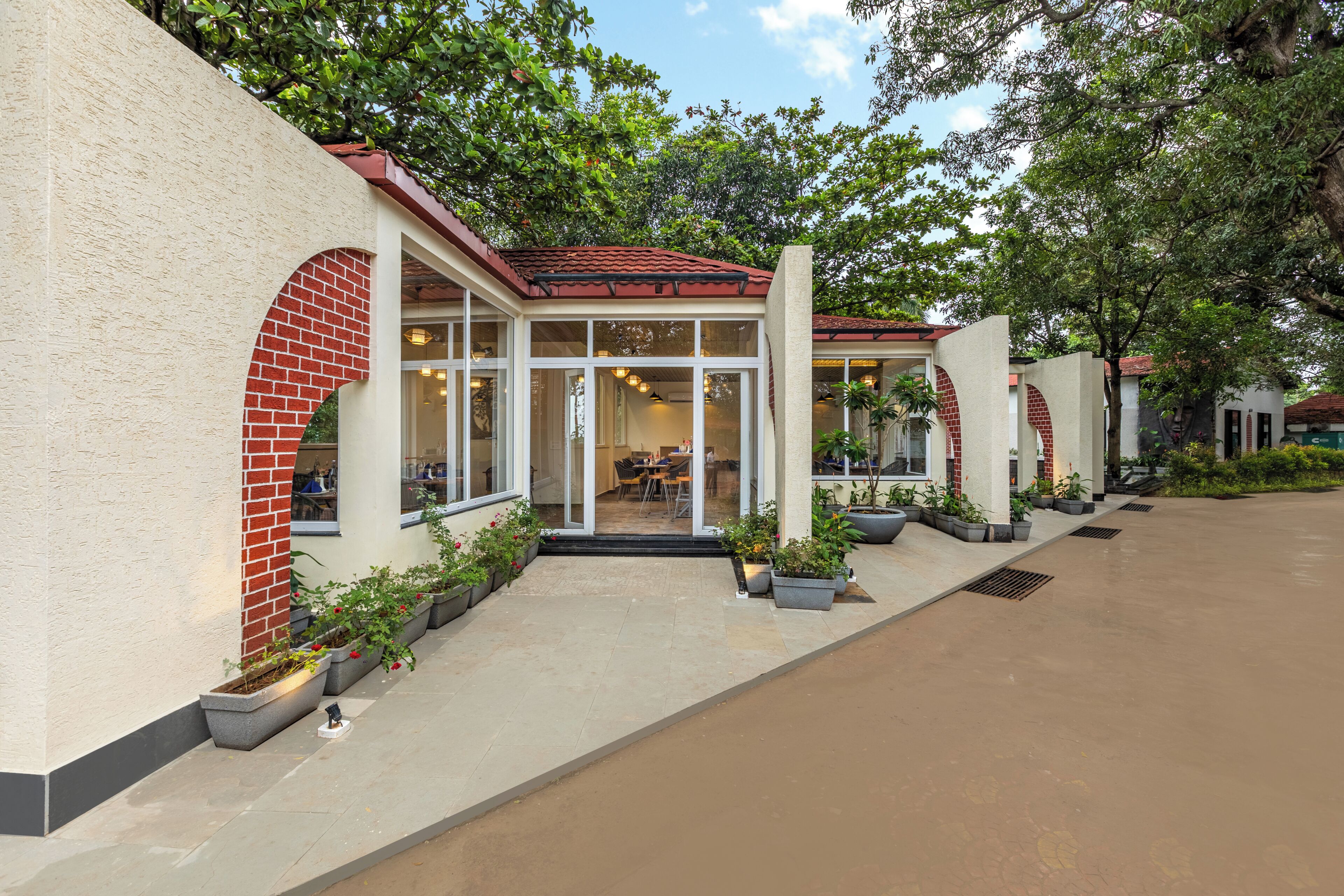 A building with a red brick archway, glass doors, and potted plants.