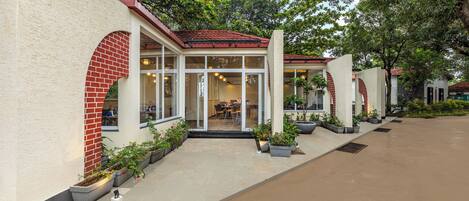 A building with a red brick archway, glass doors, and potted plants.