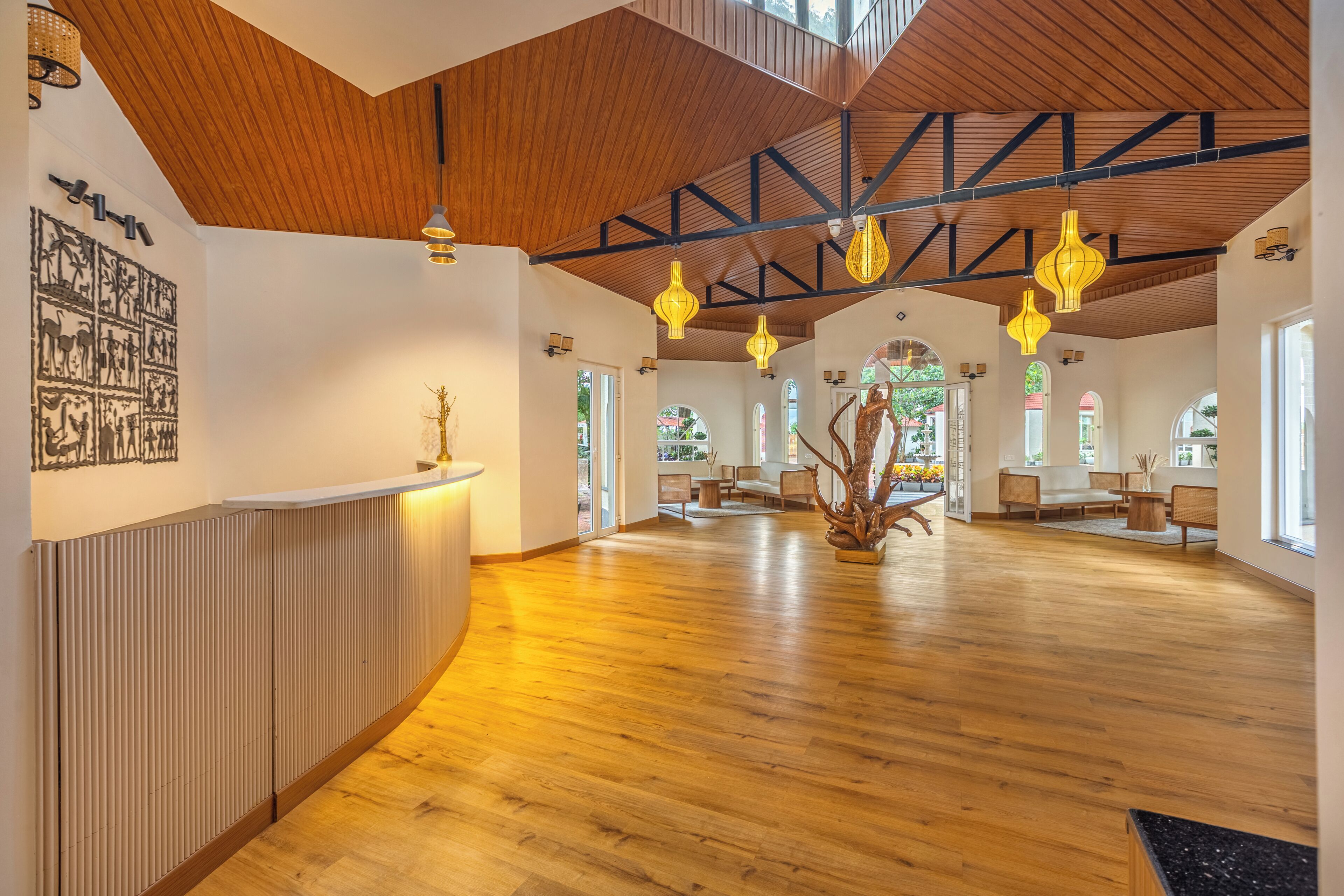 A spacious lobby with wooden floors, a reception desk, and a large sculpture.