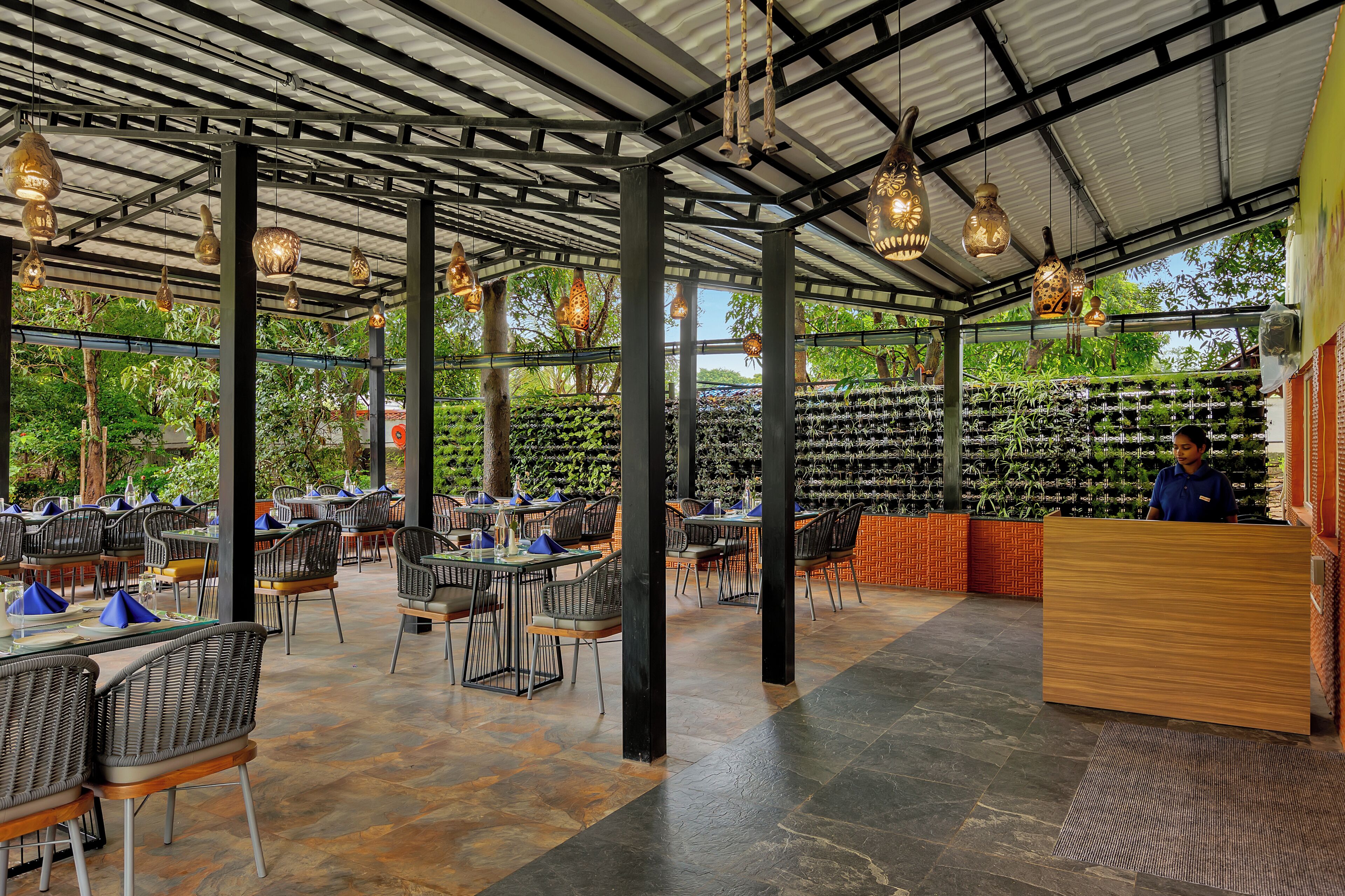 Un restaurante interior con mesas, sillas, una recepción y lámparas colgantes.