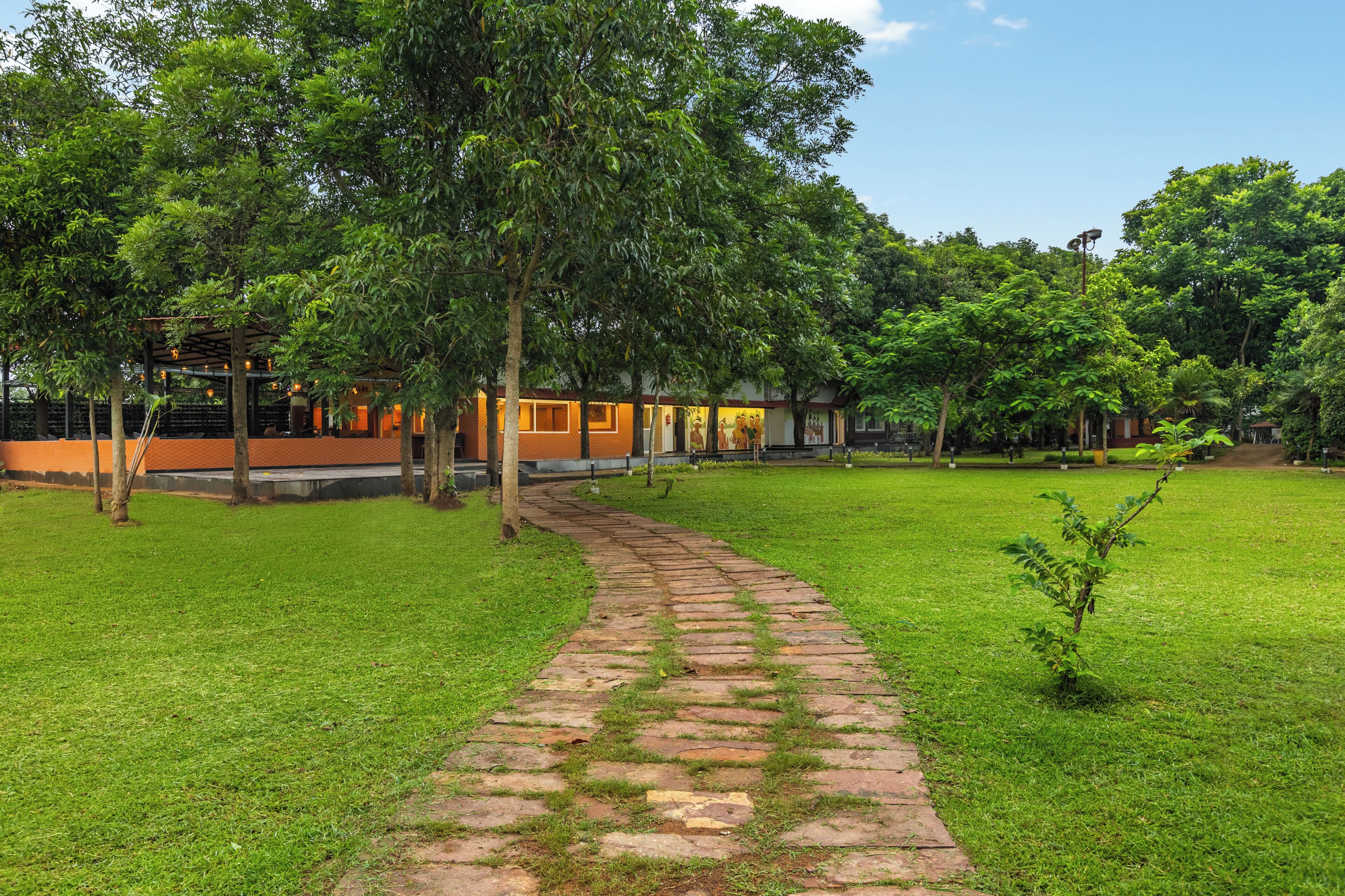 A pathway leading to a building with a brick facade and a green lawn.