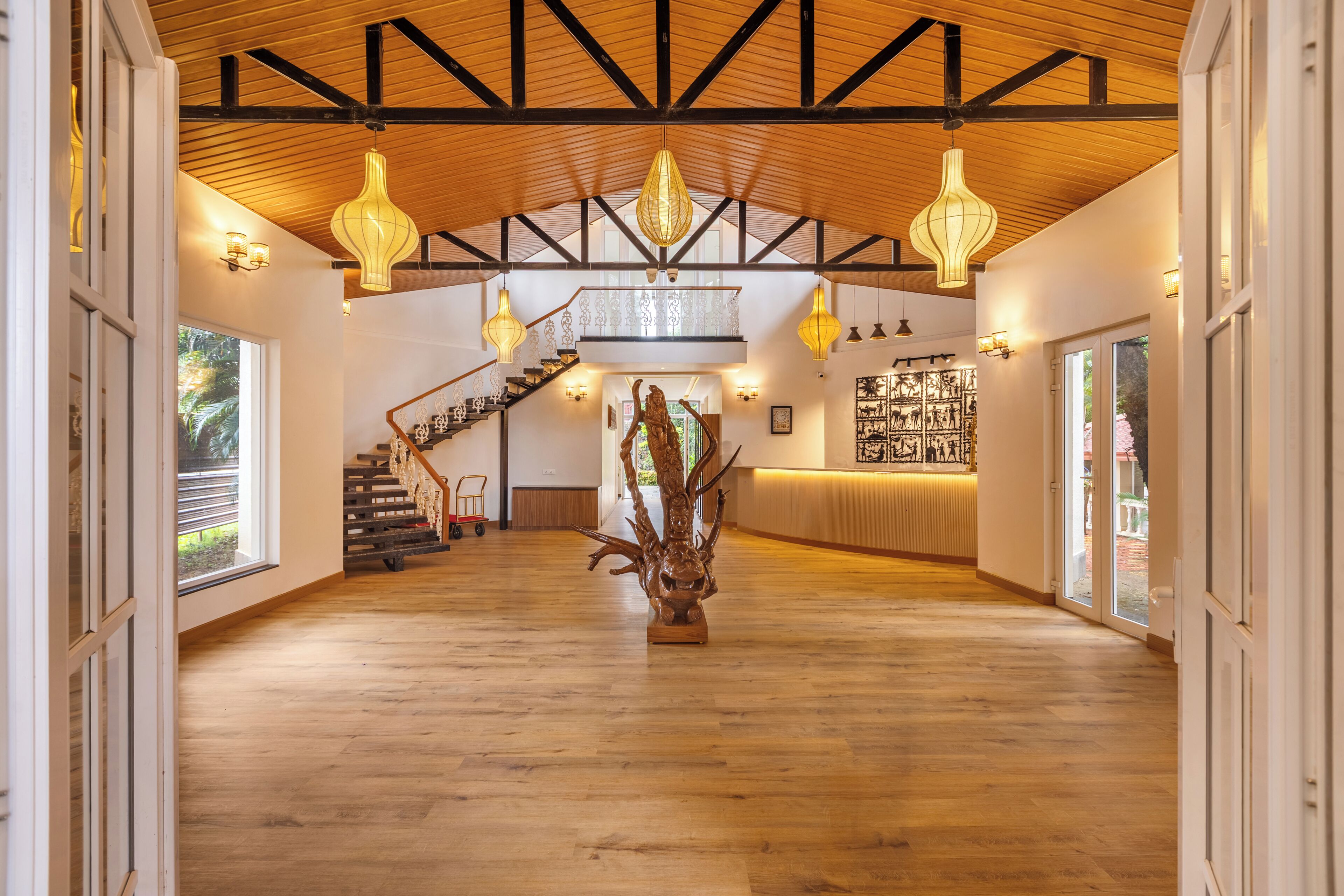 A spacious interior with a high ceiling, wooden beams, and a central staircase.