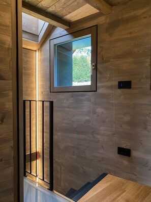 A wooden interior with a skylight, a small window, and a modern light fixture. - AffittiPontediLegno - Chalet Baita Aria (Passo del Tonale)