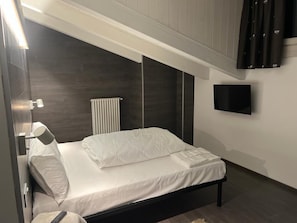 Ein modernes Schlafzimmer mit einem Bett, einem an der Wand befestigten Fernseher und einer Heizung.
