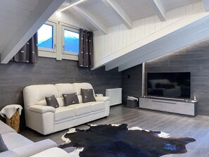 Ein modernes Wohnzimmer mit einem weißen Sofa, einem großen Flachbildfernseher und einem weichen Teppich aus Rindsleder.
