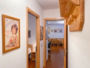 A hallway with a wooden door leading to a dining area with a wooden table and chairs. - AffittiPontediLegno - Qui e Ora House (Ponte di legno)