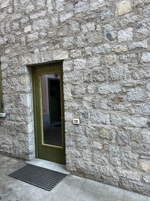 A stone building with a green door and a small window. - AffittiPontediLegno - Qui e Ora House (Ponte di legno)