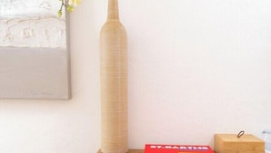 Un escritorio de madera con un jarrón de flores blancas, un libro rojo titulado 'ST. BARTHES' y una pequeña caja de madera.