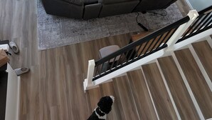 A modern living room with a sectional sofa, a large rug, and a staircase leading to an outdoor deck.
