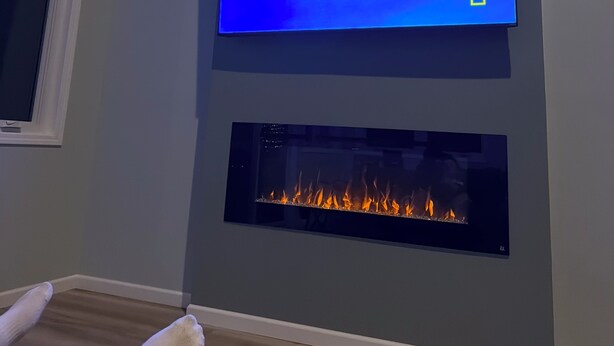 A room with a flat-screen TV mounted above a fireplace.