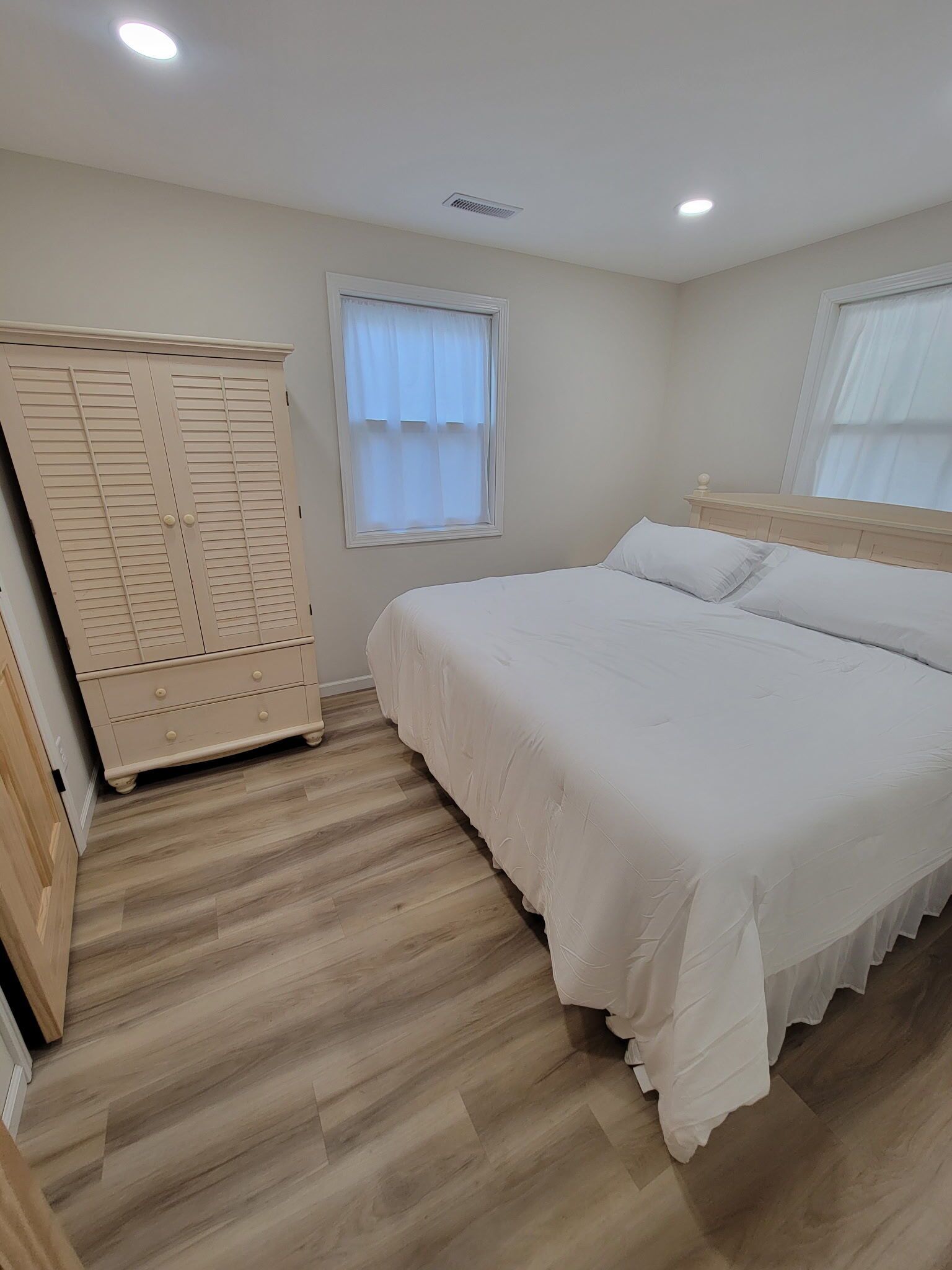 Un dormitorio con cama, armario, ventana y luz en el techo.