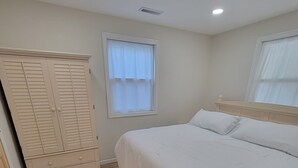 A bedroom with a bed, a wardrobe, a window, and a ceiling light.