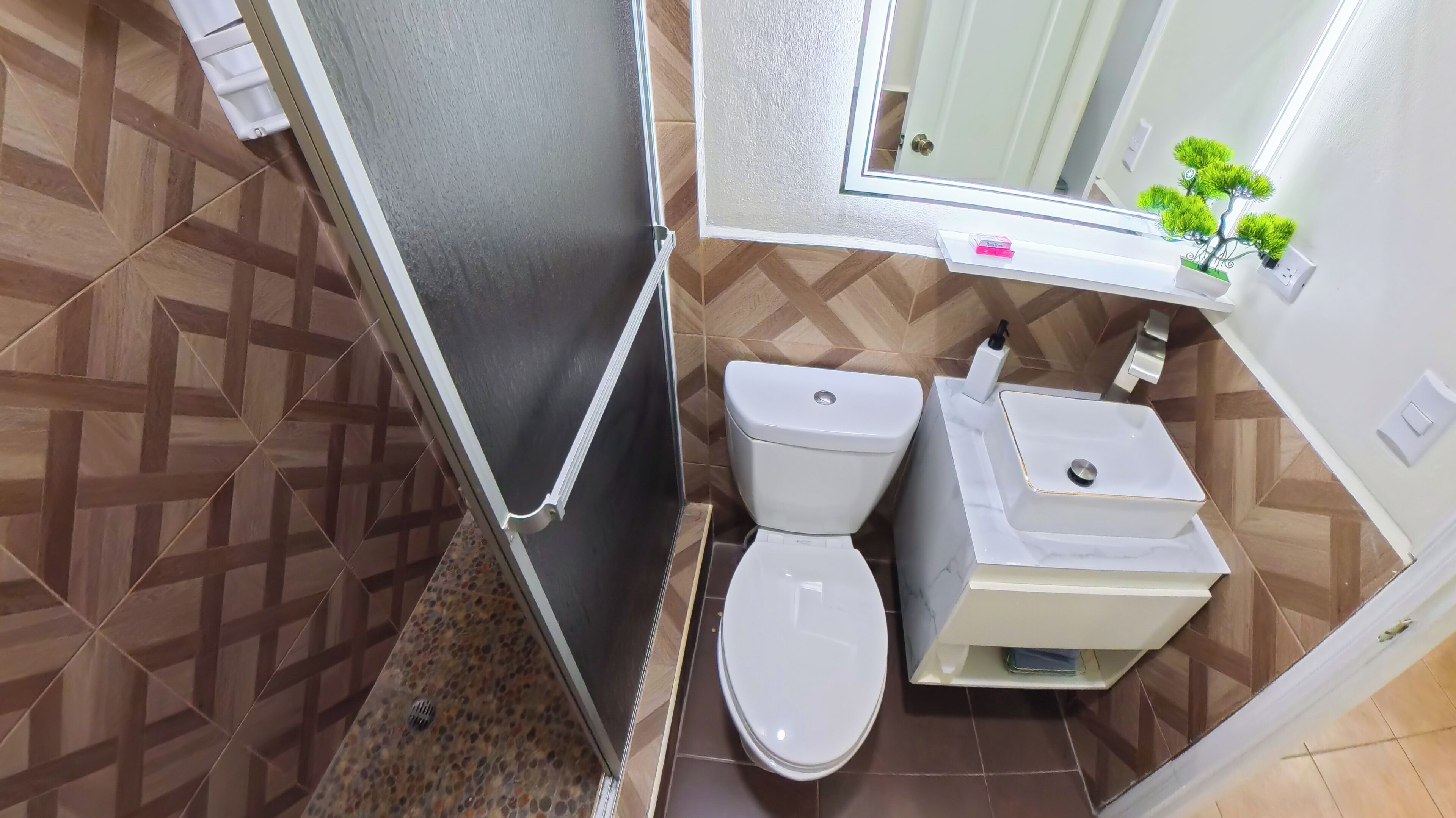 A bathroom with a toilet, sink, and mirror.