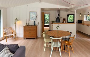 A cozy room with a wooden dining table, chairs, a dresser, and a lamp. - 3 bedroom awesome home in Svaneke (Svaneke)