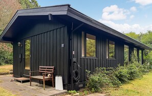 A small, dark wooden cabin with a bench and a doorbell outside. - 3 bedroom awesome home in Svaneke (Svaneke)