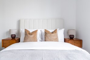 A bed with a white headboard, two nightstands with lamps, and two pillows. - Blueground | First Hill, rooftop pool, nr Seattle Art Museum (Seattle)