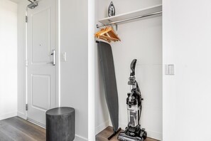 A room with a white door, a black trash bin, and a vacuum cleaner on the floor. - Blueground | First Hill, rooftop pool, nr Seattle Art Museum (Seattle)