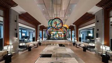 A spacious lobby with a central circular light fixture, seating areas, and a modern architectural design.