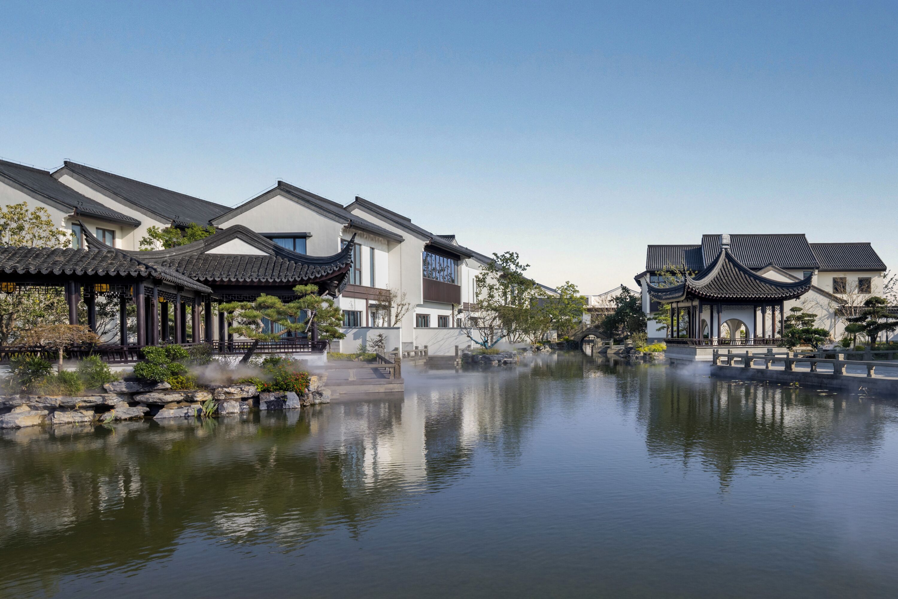 A traditional Chinese courtyard with a calm water feature, reflecting the buildings.