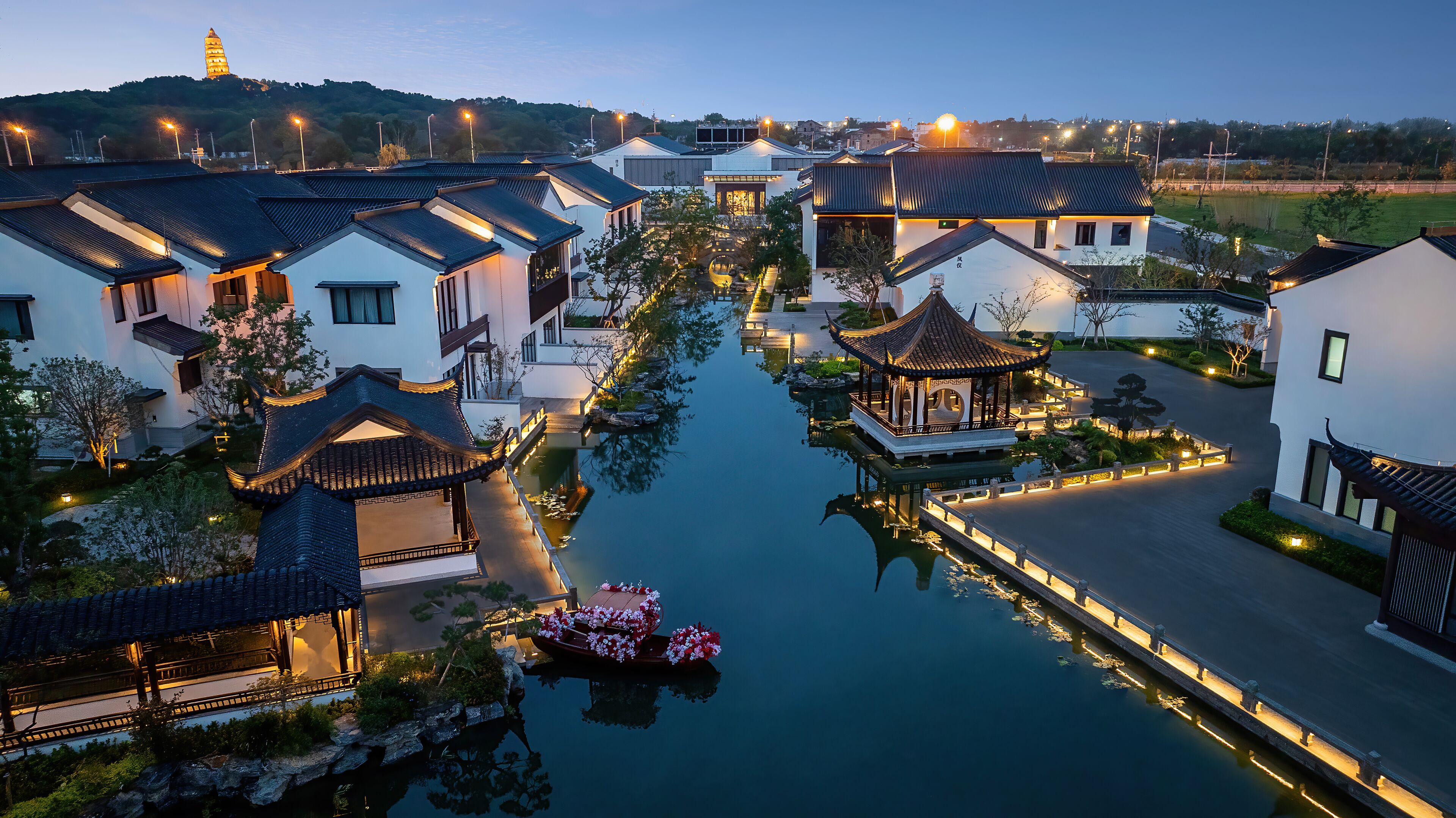 Un patio chino tradicional con agua, edificios y una pagoda.