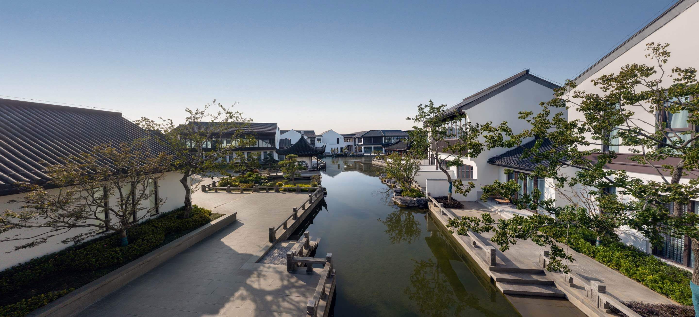 A serene courtyard with a canal, traditional buildings, and a modern structure.
