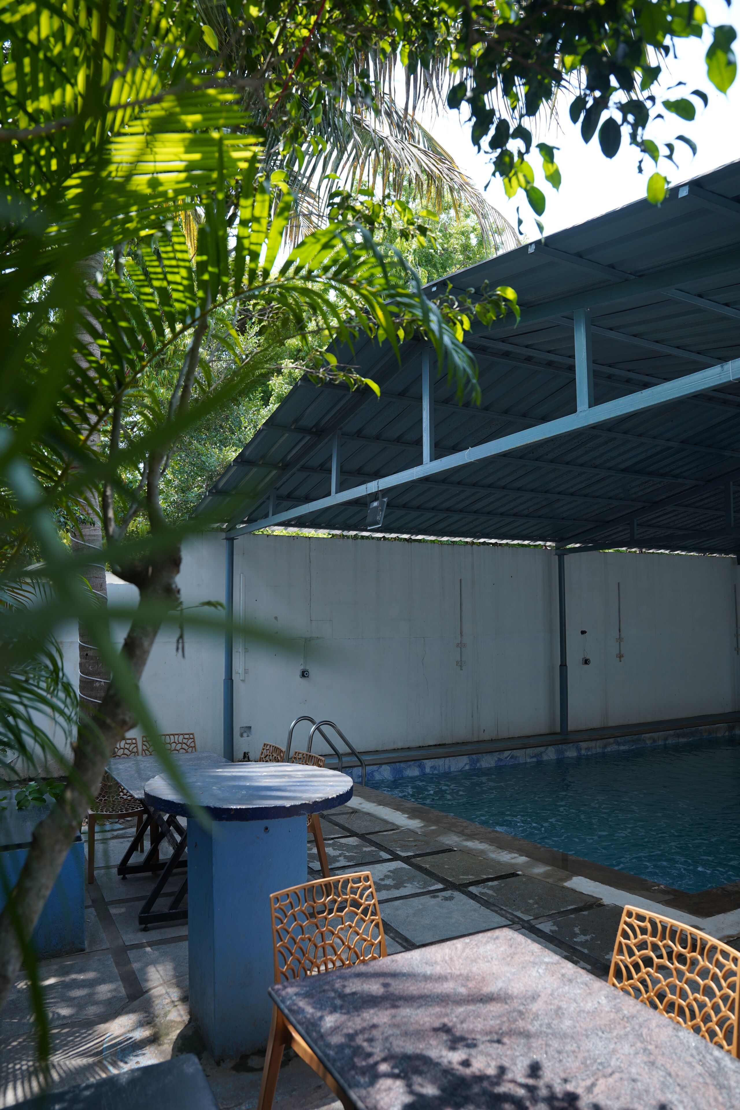 Uma área de piscina com seção coberta, uma mesa e cadeiras.