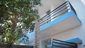 Un edificio de varios pisos con balcones y un árbol en primer plano.