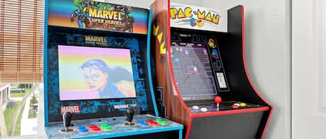 Two arcade machines, one for Marvel Super Heroes and the other for Pac-Man, with joysticks and colorful buttons.