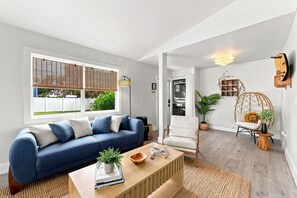 Una sala de estar moderna con un sofá azul, una mesa de centro de madera y un sillón blanco.