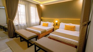 Habitación de hotel con dos camas, un banco y una mesita de noche.