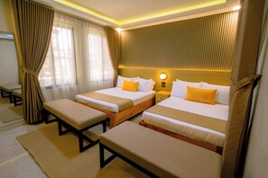 A hotel room with two beds, a bench, and a bedside table.