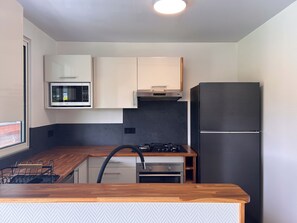 A compact kitchen with a microwave, stove, oven, and a refrigerator. - Villa Noa Vai • Swimming Pool & Lagoon Access by Kayak (papetoai)