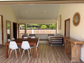 A spacious room with a wooden dining table and chairs, a sofa, and a wooden bench. - Villa Noa Vai • Swimming Pool & Lagoon Access by Kayak (papetoai)
