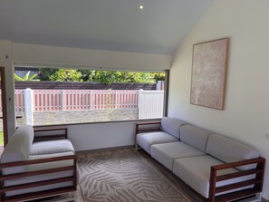 Um quarto com um sofá branco, um banco de madeira e um tapete estampado.