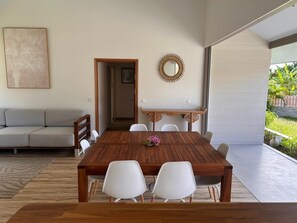 A modern dining area with a wooden table and white chairs, a wooden sideboard, and a decorative mirror. - Villa Noa Vai • Swimming Pool & Lagoon Access by Kayak (papetoai)
