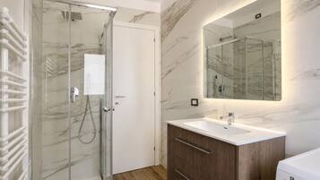 Un bagno moderno con cabina doccia in vetro, mobile lavabo in legno e uno specchio grande.