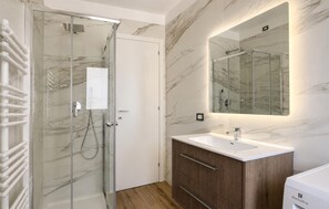Une salle de bain moderne avec une douche à parois de verre, un meuble-lavabo en bois et un grand miroir.