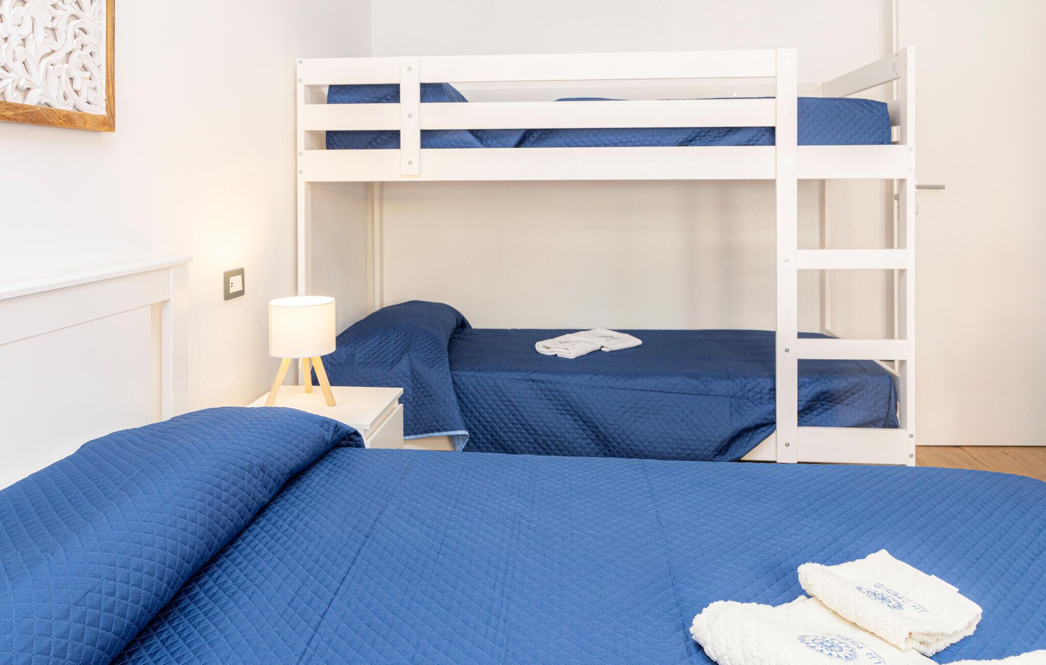 Une chambre avec un lit superposé, comprenant deux lits, une table de chevet avec une lampe et un élément décoratif mural.