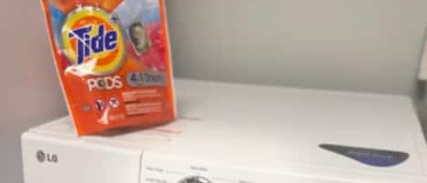 A front-loading LG washing machine with Tide Pods on top.