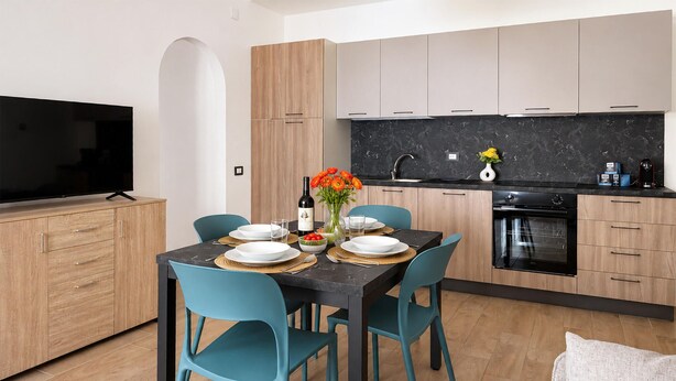 A modern kitchen with a dining table set for two, a TV, and a sink. - Maison marina Suite - Mykonos (Paola)