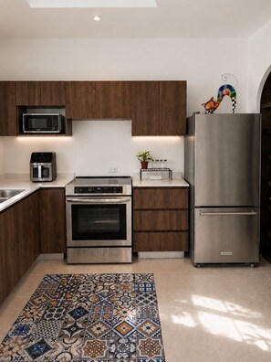 A modern kitchen with built-in appliances, a patterned rug, and wooden cabinetry.
