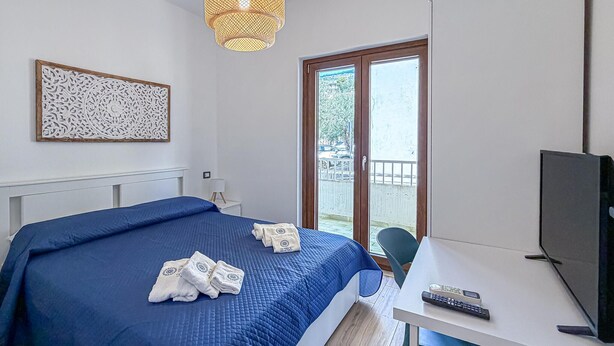 Habitación de hotel con cama, escritorio con televisor, ventana y un adorno en la pared.
