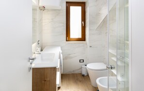 Une salle de bain compacte comprenant un espace douche, des toilettes et un lavabo.