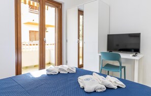 A hotel room with a bed, a TV, a desk, and a chair. - Maison marina Suite- Santorini (Paola)