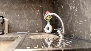 Un lavamanos de cocina con un grifo moderno, un pequeño jarrón blanco con flores y un tapete azul en la encimera.