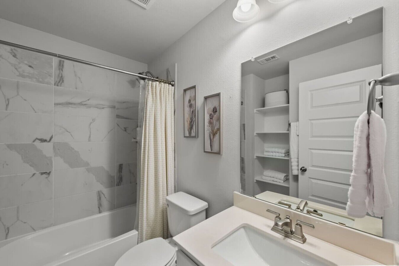 Un bagno con doccia, WC, lavandino e uno specchio grande.