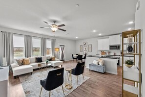 Un espacio habitable moderno con sofá, comedor, cocina y ventilador de techo.