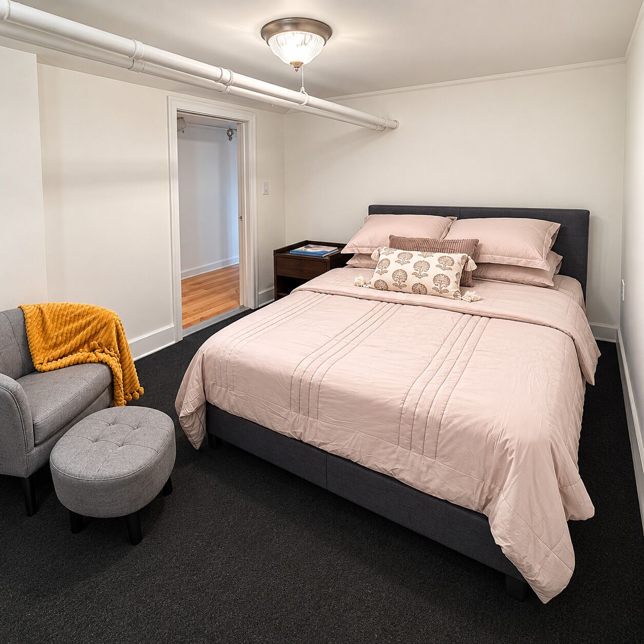 A bedroom with a bed, a nightstand, a chair, and a window.