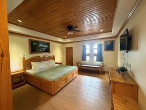 Un dormitorio con techo de madera, una cama, un escritorio y una silla.